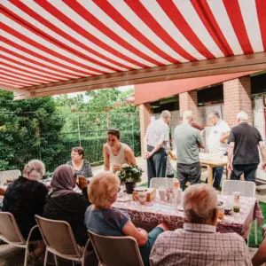 Buurtbewoners praten met elkaar aan lange tafel op straat