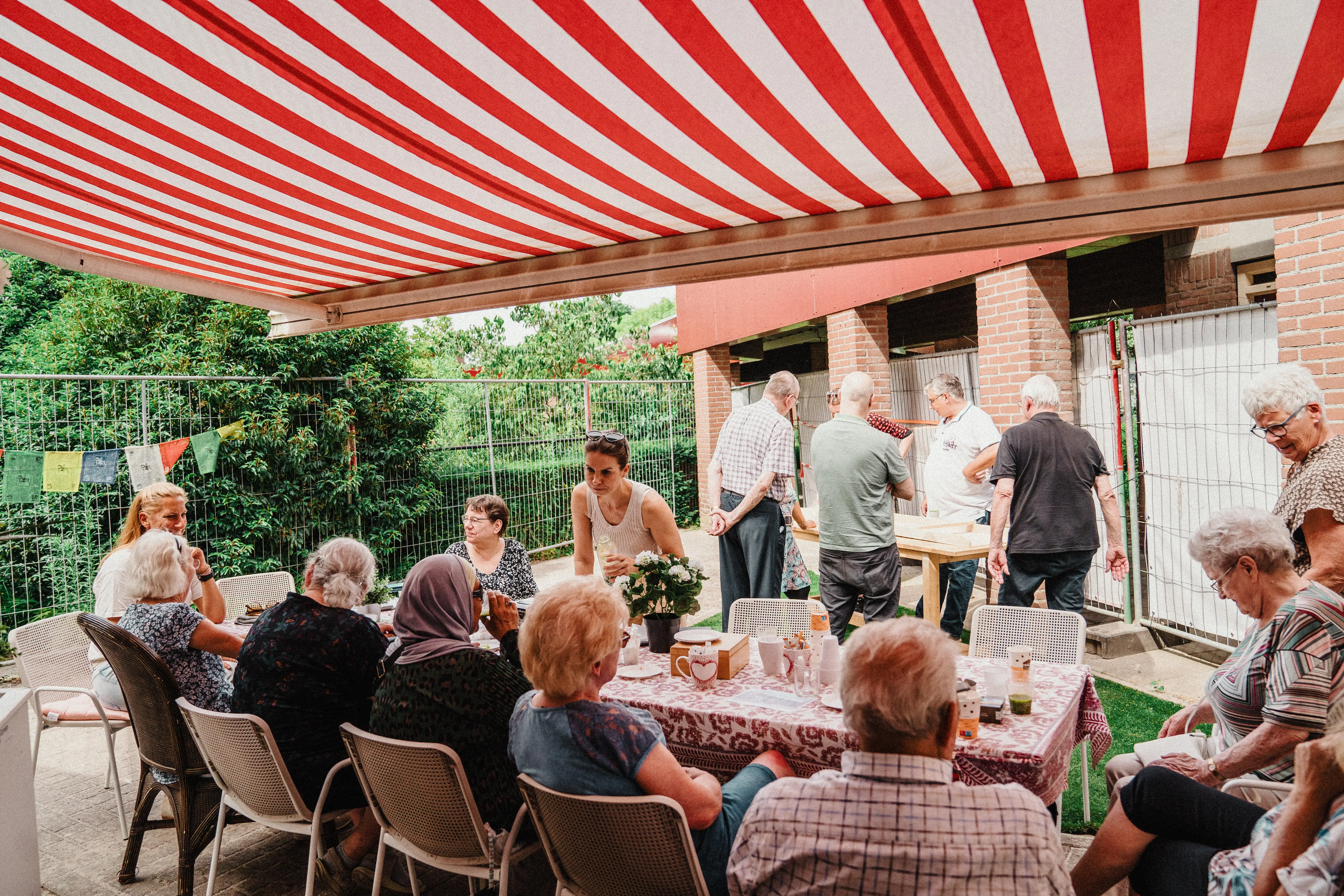 Buurtbewoners praten met elkaar aan lange tafel op straat
